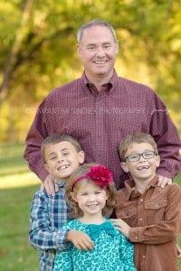 children poses for a photo with their father