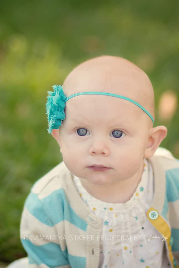 toddler girl with blue eyes smiles at Samantha sinchek photography camera